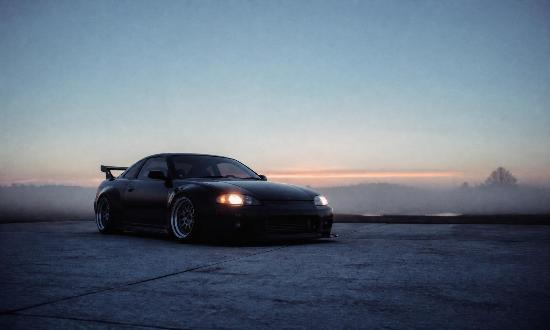 A modified car parked on an empty lot at dawn